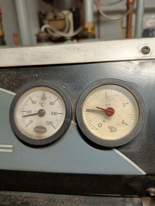 Manometer och temperaturmätare på en panna, visar tryck i bar och temperatur i grader Celsius.