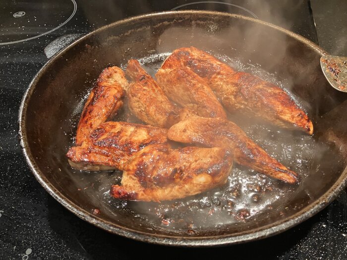 Kycklingbitar som steks i en panna.