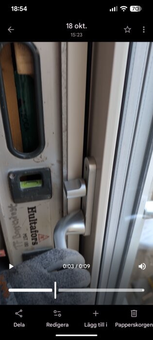 Närbild på en altandörr från Elitfönster med en monterad dörrkarm och ett vattenpass från Hultafors för att kontrollera lod.