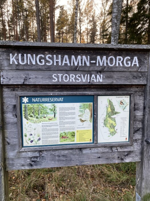Skylt för KUNGS HAMN-MORGA naturreservat med information och karta över området, omgiven av skog.