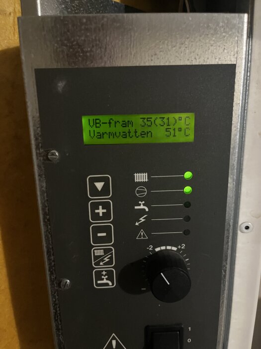 Display på värmepump visar temperaturer: VB-fram 35°C, varmvatten 51°C; grön diod lyser. Reglage och symboler på panelen syns.