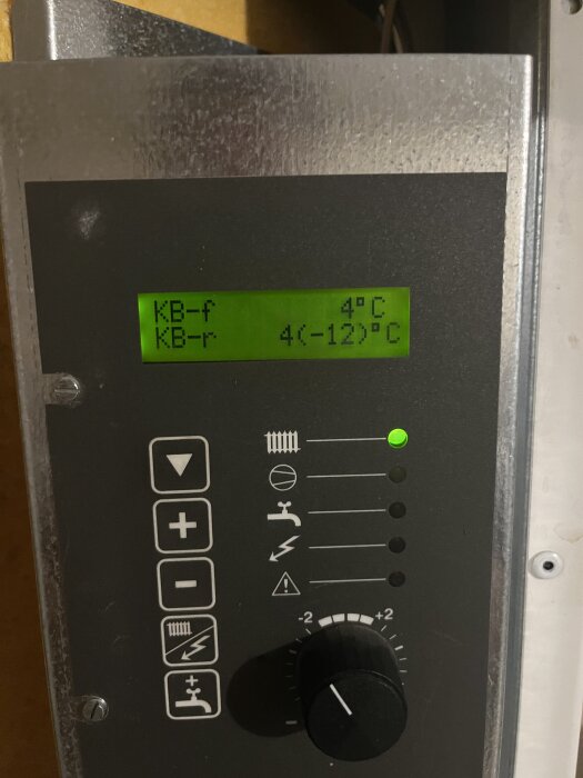 Display på värmepump med temperaturvärden, visande "KB-f 4°C" och "KB-r 4(<12)°C", samt kontroller och lysande indikatorlampa.