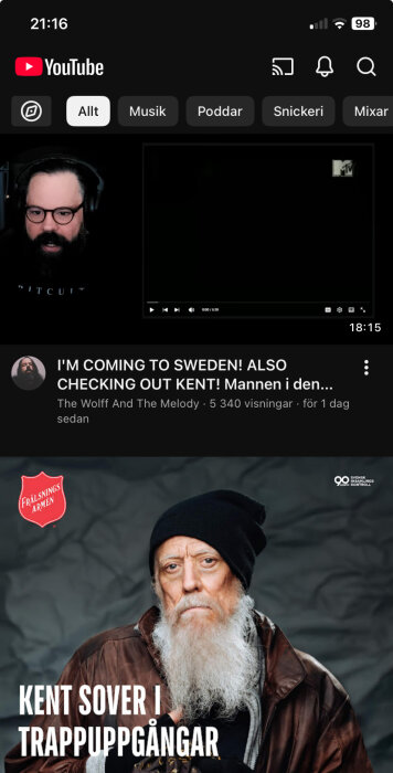 En YouTube-skärmdump med video om Kent. Texten "KENT SOVER I TRAPPOPPGÅNGAR" syns, med person i mössa och skägg.