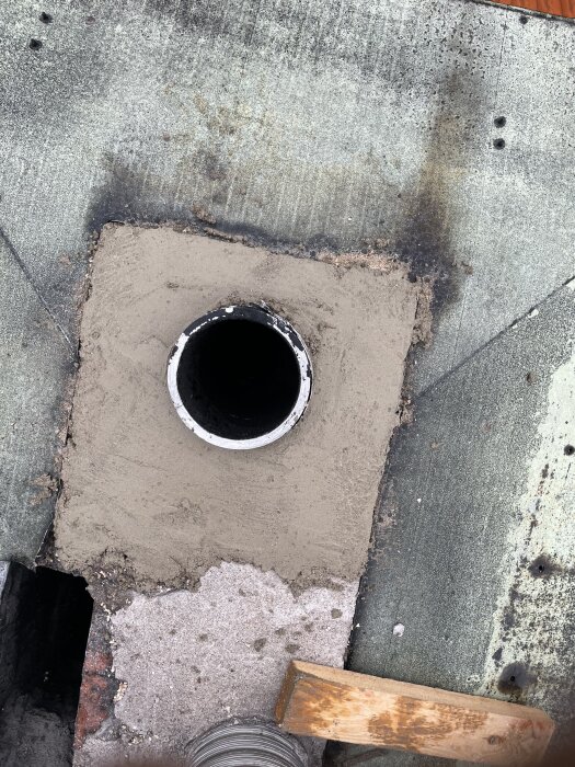 En nygjuten pipöppning i ett kökstak med synlig metallinsats och omgivande cement, processen beskriven i ett forum om gör-det-själv-renovering.