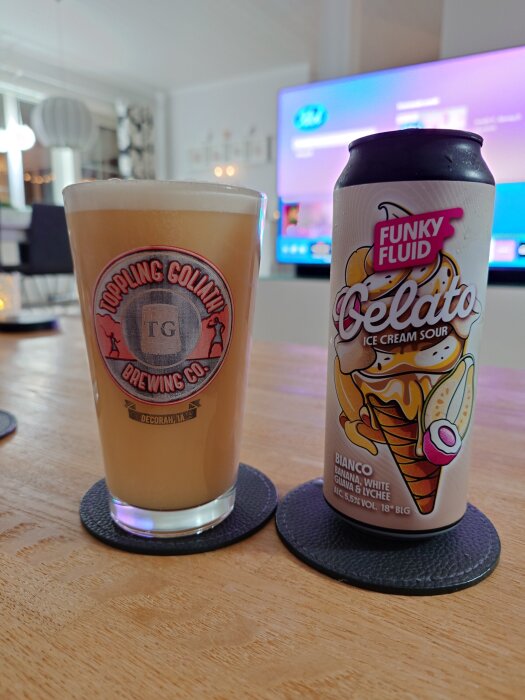 Öl från Toppling Goliath i glas bredvid en burk Funky Fluid Gelato Ice Cream Sour på ett bord.