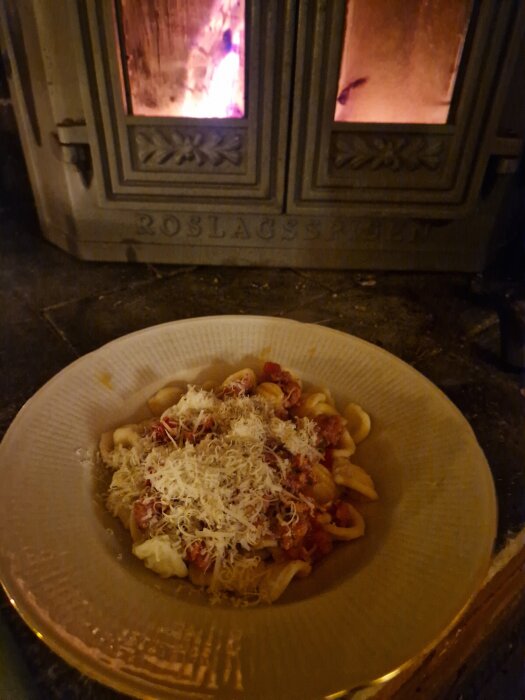 Pasta orecchiette med salsiccia och riven parmesan framför en tänd braskamin, i en rustik stuga i Stockholms skärgård.