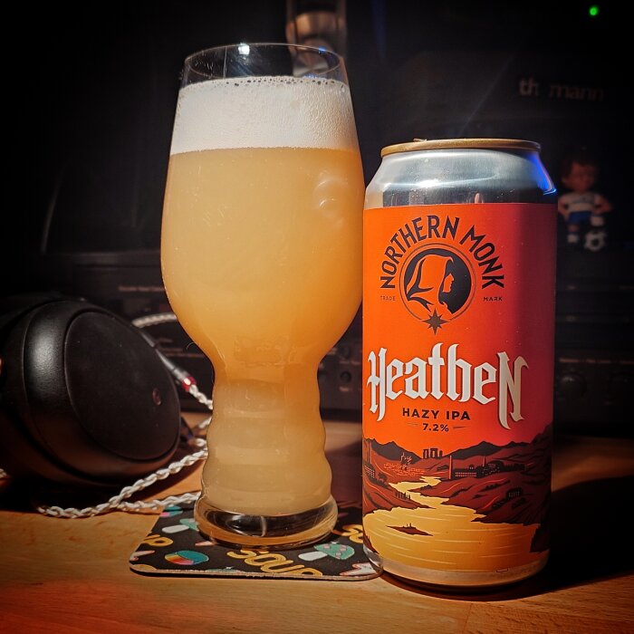 Northern Monk Heathen Hazy IPA 7.2% bredvid ett glas med skummande, grumlig IPA på ett underlägg.