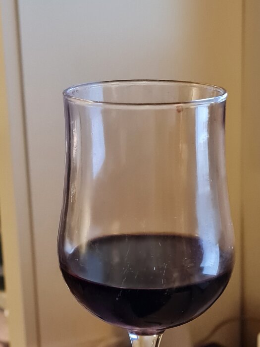 Ett glas rött vin, troligen Lynx Petite Sirah Zinfandel, mot en suddig bakgrund.