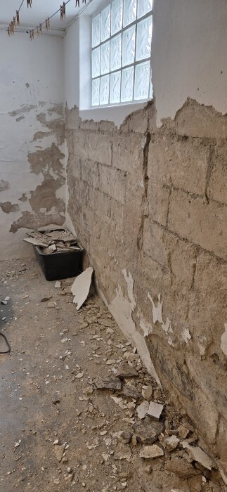 Skadad puts i en källare från 1943 med synlig tegelvägg och byggrester på golvet under pågående renovering.