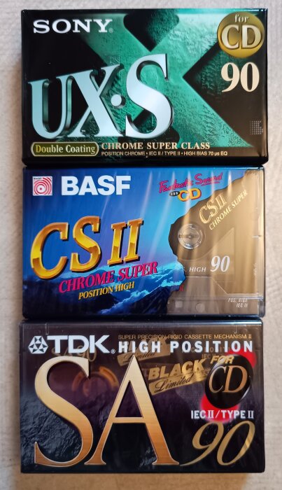 Tre kassettband från SONY, BASF och TDK, med färgglada förpackningar och texter om typ och längd, fotograferade i en stapel.
