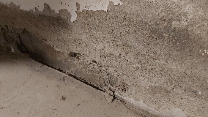 Flagnande och smulande källarvägg med synliga skador och sprickor, orsakad av nedbrytning eller fuktproblem.