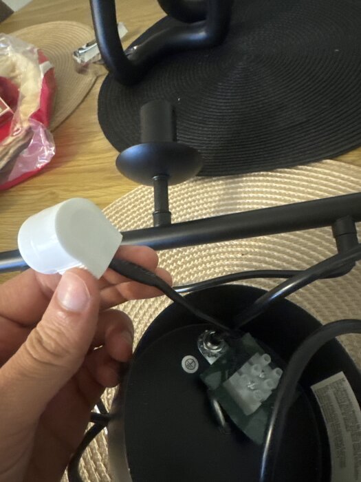 En person håller en kopplingsdosa med en kabel ansluten, medan två andra kablar är oanslutna vid ett takfäste.