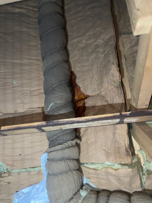 Fuktfläckar vid isolering och ett rör på vinden, indikerar möjlig läcka eller fuktproblem.