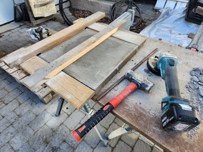 Verktyg och stenar på arbetsbänk för reparation av murens toppstenar.