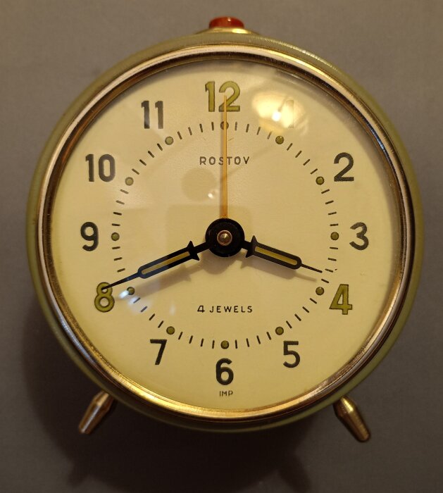 Väckarklocka från Rostov na Donu med guldram och arabisk nummerskala, som ska rengöras och smörjas. Visarna visar tiden 10:08.