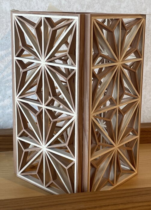 Kumiko-lyktor med geometriska mönster i ask och redwood, placerade på en trähylla.