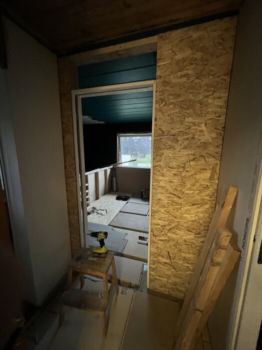 Installation av skjutdörr med pocketkarm på en vägg av spånskivor, med verktyg och material synliga på golvet.