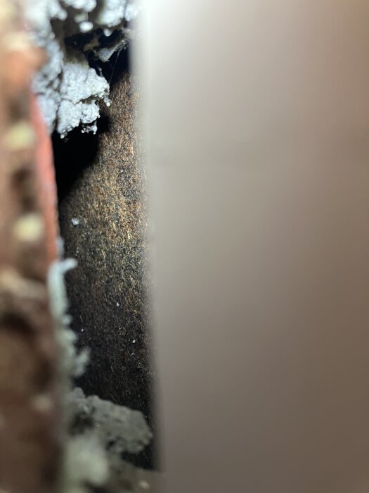 Bilden visar en del av en vägg med skadad isolering. Möjligen en gammal ångbroms, omgiven av trä och gips.