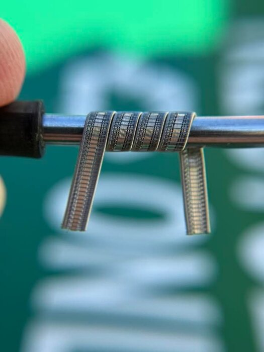 Närbild av specialtillverkade vejp-coils snurrade av nichrome-tråd, monterade på en stav för visning av viklingsteknik.