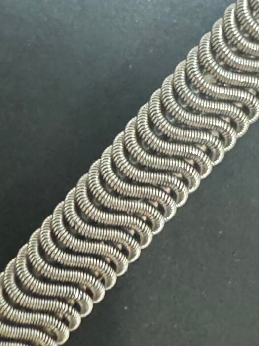 Närbild av en clapton coil tillverkad av nichrome-tråd, där en tunnare tråd är lindad runt två tjockare trådar för att skapa ett spiralmönster.