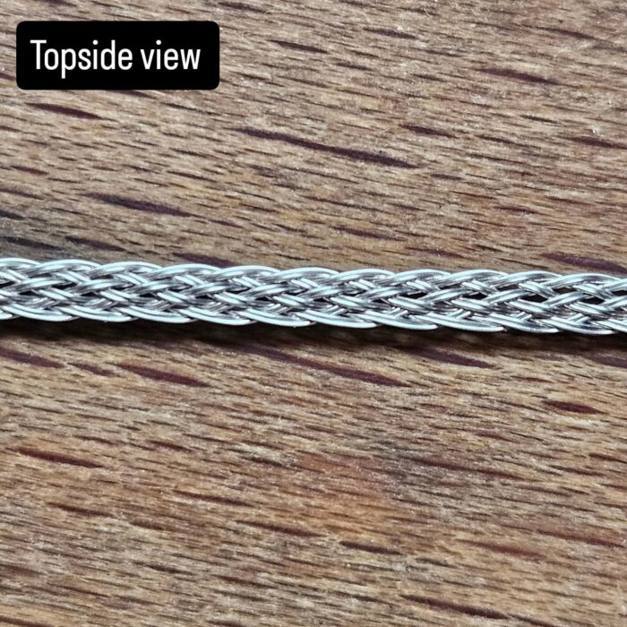 Närbild av en handgjord clapton coil av sammanflätade nichrome trådar, fotograferad ovanifrån på en träyta.