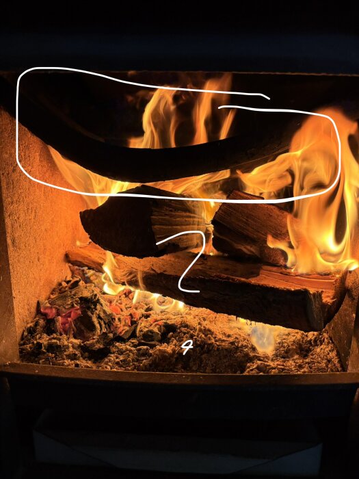 Braskamin Morsö 4132 med rökhylla markerad, omgiven av brinnande ved och aska.