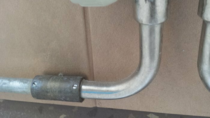 Radiatorkoppel i metall med synlig bypass i ett värmesystem, monterad mot en vägg.