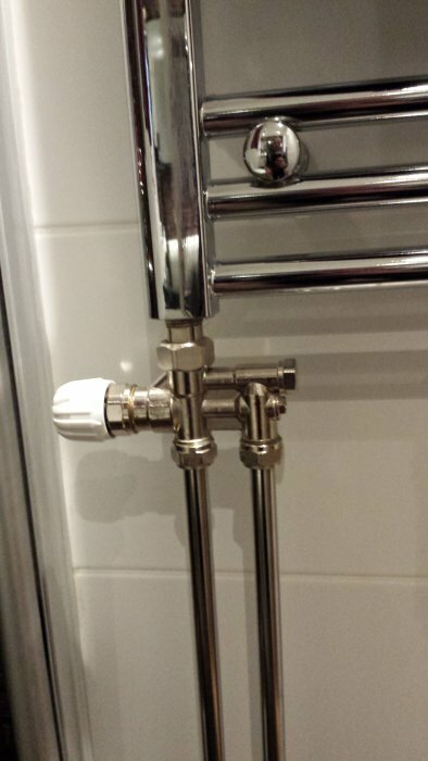 Radiatorkoppel med ventiler och rör i metallanslutning i ett badrum, eventuellt för ett- eller tvårörsystem.
