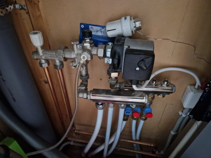 Värmeinstallation med rör, ventiler och en cirkulationspump i källare, del av golvvärmesystemet.