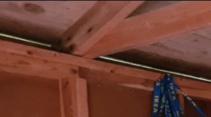 Sammanfogning av takstolsben och hanbjälke i gammal gäststuga, träkonstruktion med IKEA-mätband synligt.