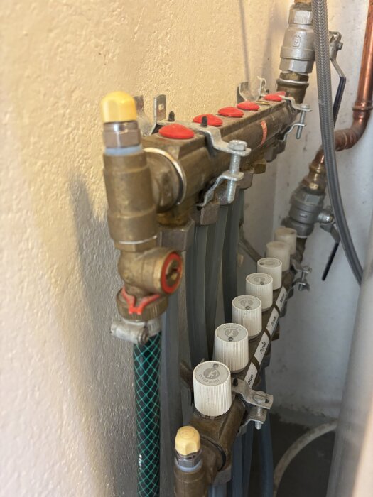 Golvvärmesystem med ventiler och slangar där framledningstemperaturen är 34 grader. Vita ventiler med texten "Giacomini" syns.