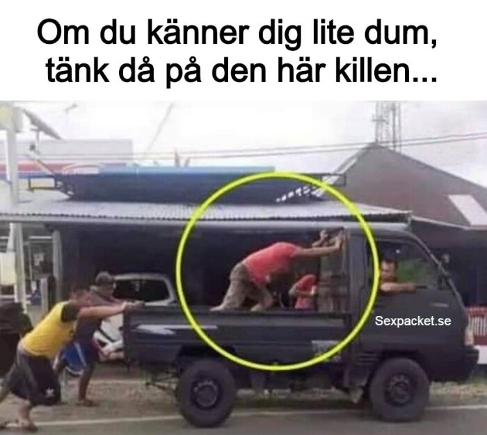 Två personer puttar en lastbil medan en man inuti försöker hjälpa till genom att skjuta på hytten med händerna.