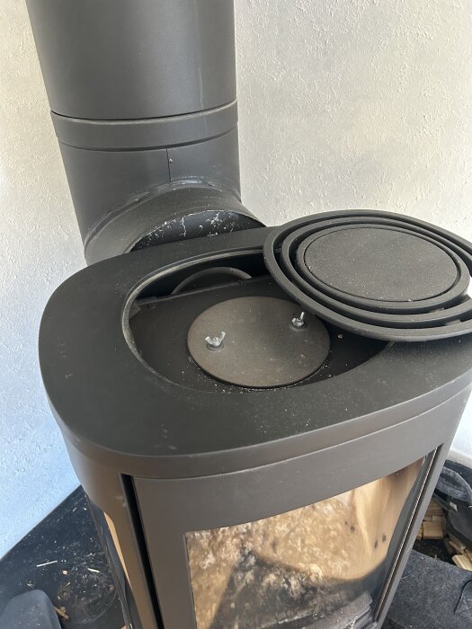 Braskamin med röranslutning bakifrån och öppen topp. Diskuteras möjlighet att öka verkningsgrad genom vertikalt rör på toppen.