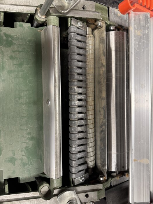 Närbild av en begagnad plan- och rikthyvel, med fokus på de slitna anti-kickback spärrhakarna som sitter fast och behöver justeras.