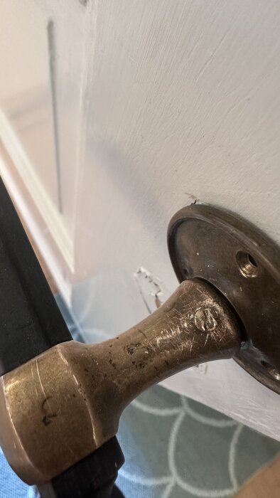 Närbild på en dörr med ett handtag där skruvhuvudet gått av. Dörren är vit och handtaget är metalliskt.