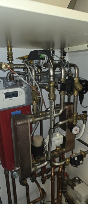 Komplext röruppkopplingssystem med mätarinstrument och ventiler, sannolikt del av ett värmesystem eller pumpinstallation.