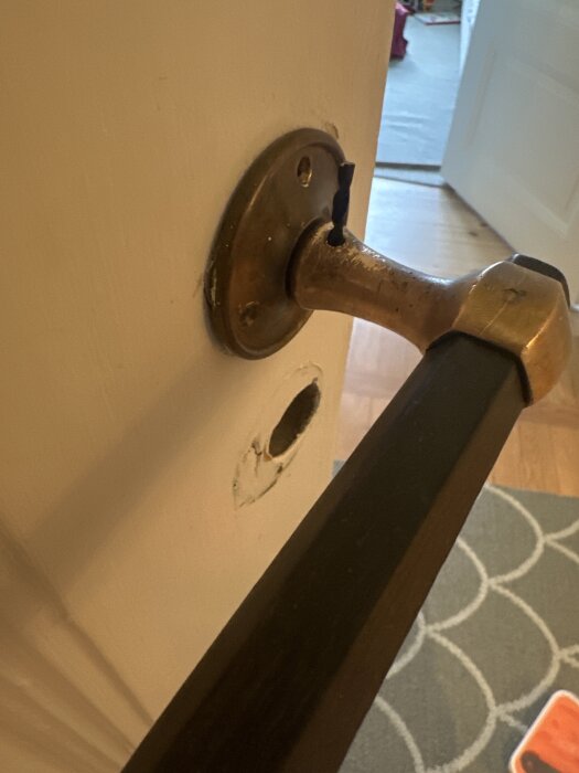 Dörrhandtag brutet från dörren, skruvhål synligt, felmonterat.