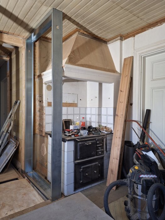 Stålreglar vid vedspis, med verktyg och material runtom; inlägg om att montera gipsskiva och mineritskiva mot stålregeln.