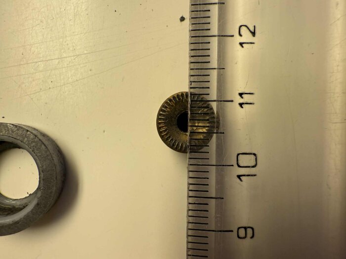 Kullagerdel från duschkabin med måttband som visar storleken, cirka 9 mm i diameter.