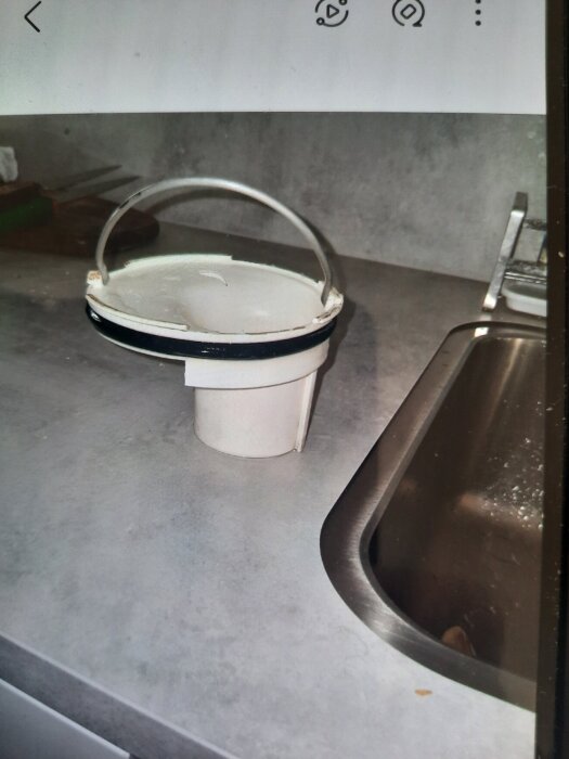 Golvbrunnsinsats med en metallbåge, märkning Ran RSK 711 80 82, på en diskbänk bredvid en diskho.