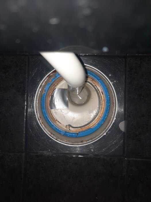 Golvbrunnsinsats med ett rör som går ner i mitten, märkt Ran RSK 711 80 82, omgiven av blå och metalliska detaljer.