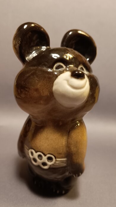 Keramikfigur av björnen Misha, maskot för OS 1980, med ett bälte med olympiska ringar.