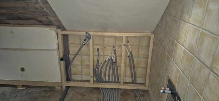 Badrum under renovering med varm- och kallvattenrör buntade ihop. Vägg under konstruktion och golvet väntar på betonggjutning.