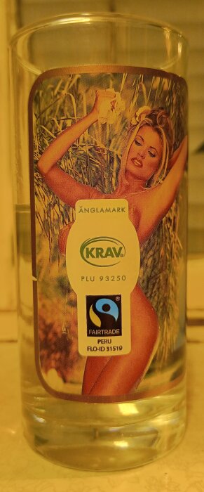 Glas med termokrom färg och tryck, censurerat med en bananetikett med texten "KRAV", "FAIRTRADE" och produktdetaljer.