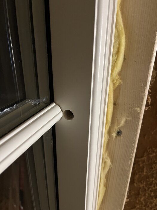 Bild på ett fönster med ett karmhål som är centrerat i höjden. Det verkar svårt att skruva åt karmhylsan utan att skada spröjset.