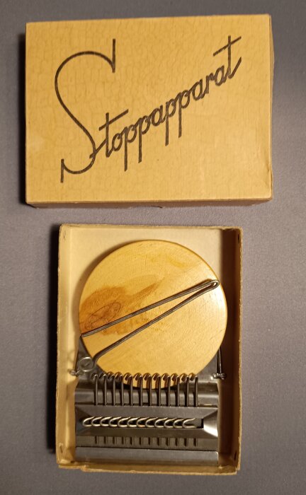 Stoppapparat från Stockholm under krigsåren, ser ut som en liten vävstol, med trådar och träram, i en kartong märkt "Stoppapparat".