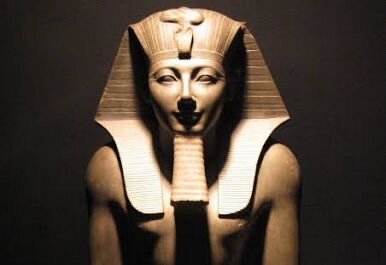 Stenskulptur av en egyptisk farao med karakteristiskt huvudbonad och upphöjd ansiktsuttryck, liknande Thutmosis III.