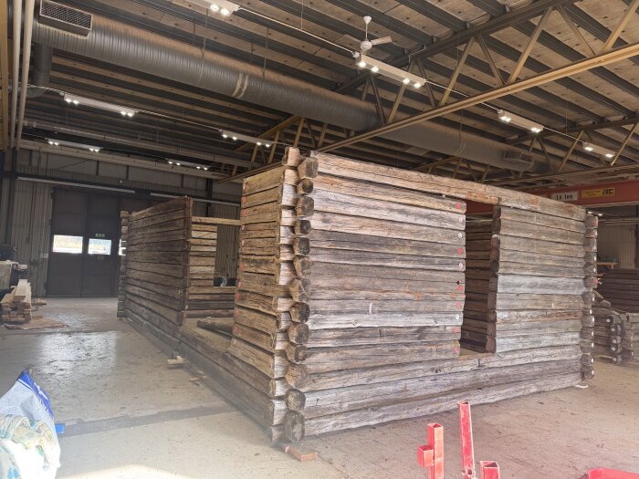 Uppmärkt och nedplockad timrad lada från 1800-talet, ursprungligen från Orsa, visas inomhus med delarna staplade och märkta.