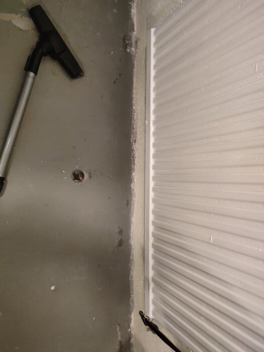 Vägg med röranslutning och dammsugarslang, obestämd funktion.