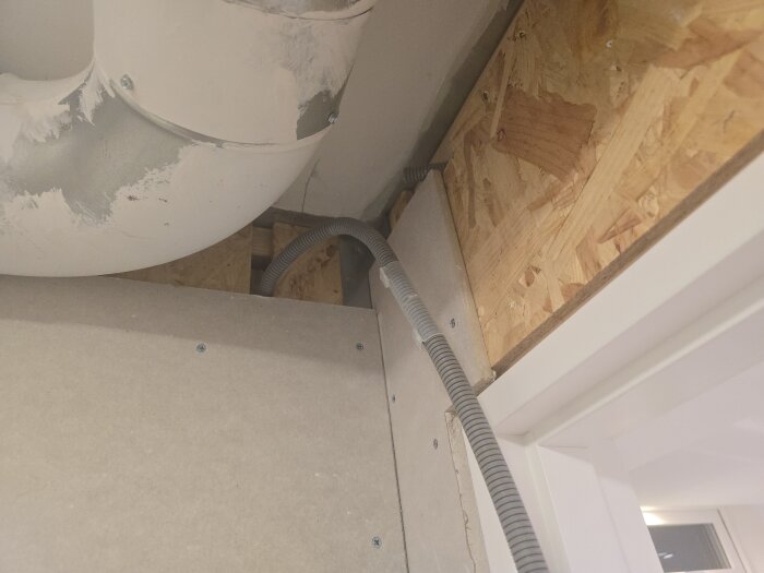 Flexrör och ventilationsrör i taket, omgiven av trä och betong, i samband med renovering.